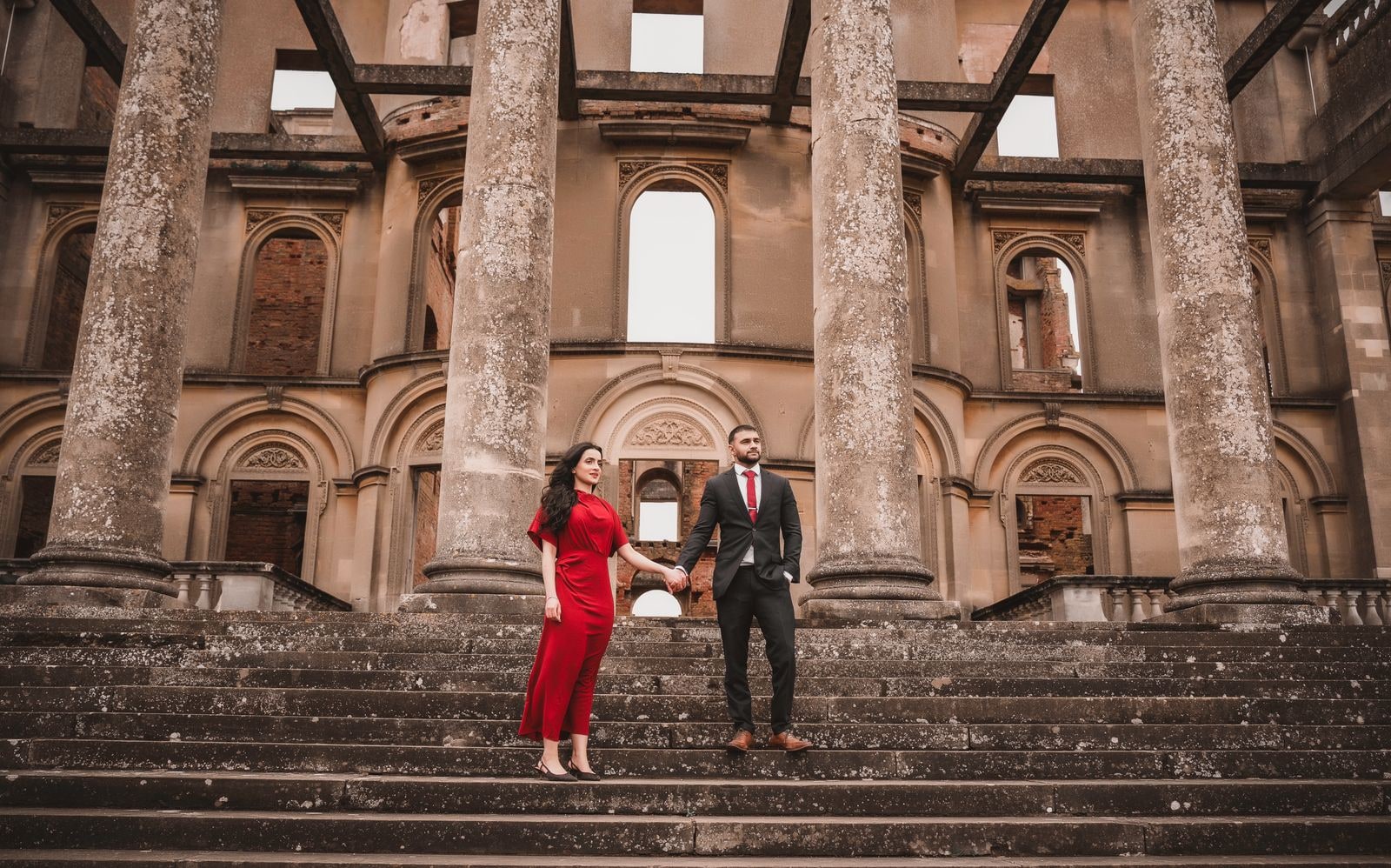 Sikh couple holding hands on the weathered stone steps of the ruined mansion at Wrest Park